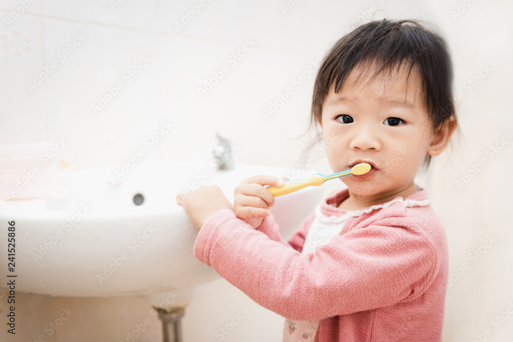 Sweet Asian child little girl brushing her teeth in bathroom Sweet Asian child little girl brushing her teeth in bathroom