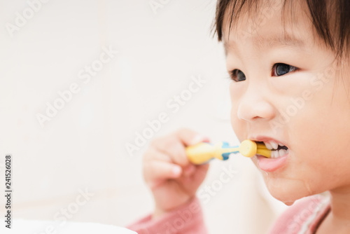 Sweet Asian child little girl brushing her teeth in bathroom