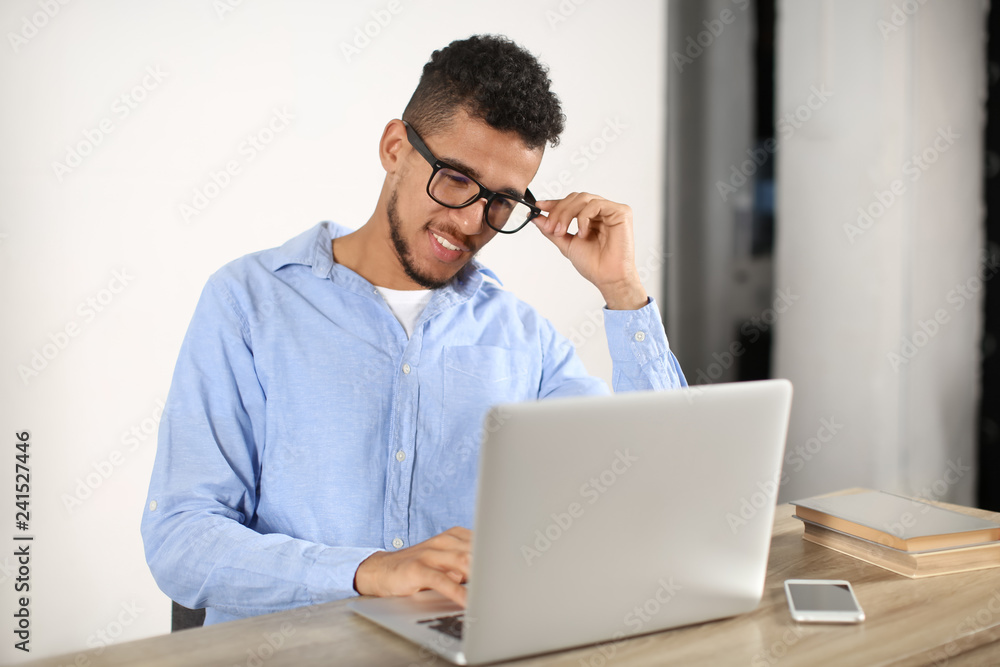 Young African-American man working with laptop in office Young African-American man working with laptop in office