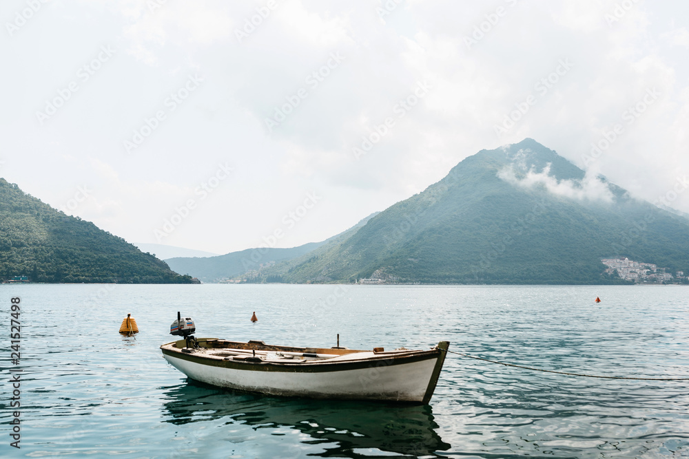 Beautiful view of the fishing motorboat in clear transparent water with reflection in the Bay of Kotor in Montenegro against the backdrop of the mountains.