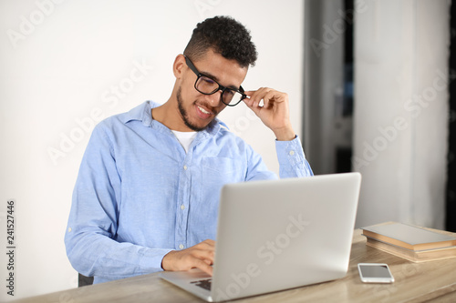 Young African-American man working with laptop in office