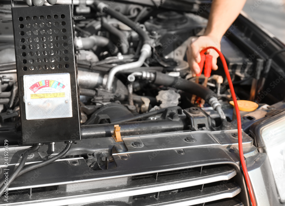 Fototapeta premium Male mechanic charging a car battery