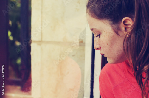 Teenager girl sad depressed looking out of a window