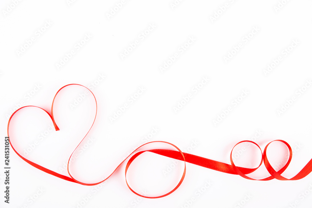 Isolated silk red ribbon laid in heart shape on bright white background. Festive decoration. Mother's, Women's, Wedding, Happy st Valentines Day concept, 14th February. Top view, flat lay, close up.