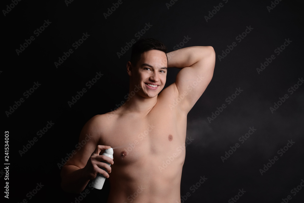 Naklejka premium Young man with deodorant on dark background