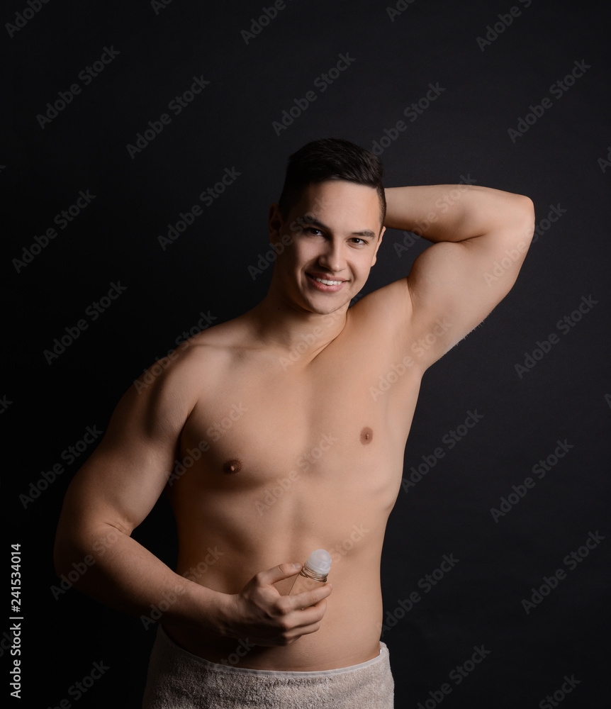 Young man with deodorant on dark background