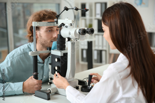 Ophthalmologist examining young man in clinic photo