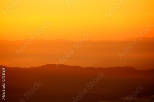 Beautiful orange sunlight or sunrise in morning with silhouette of big mountain for background at Doi Chiang Dao, Doi Luang Chiang Dao, Chiangmai, Thailand -Landmark and Beauty of Nature concept