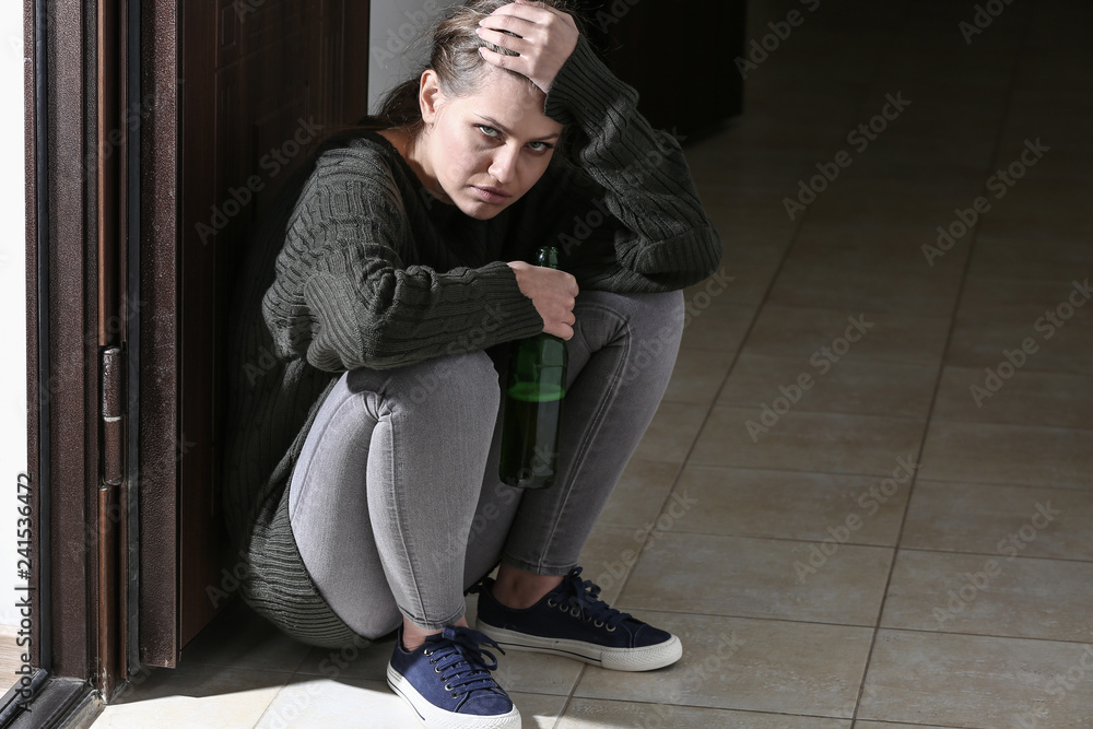 Depressed woman drinking alcohol in corridor Depressed woman drinking alcohol in corridor