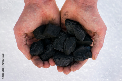 hands hold a handful of coal
