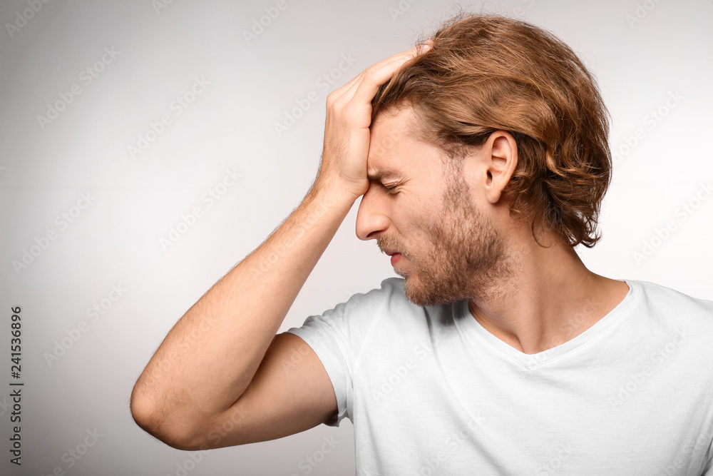 Young man suffering from headache on light background Young man suffering from headache on light background