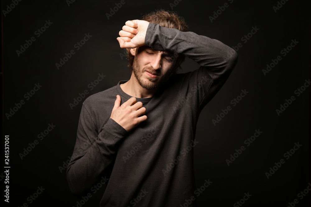 Young man suffering from headache on dark background Young man suffering from headache on dark background