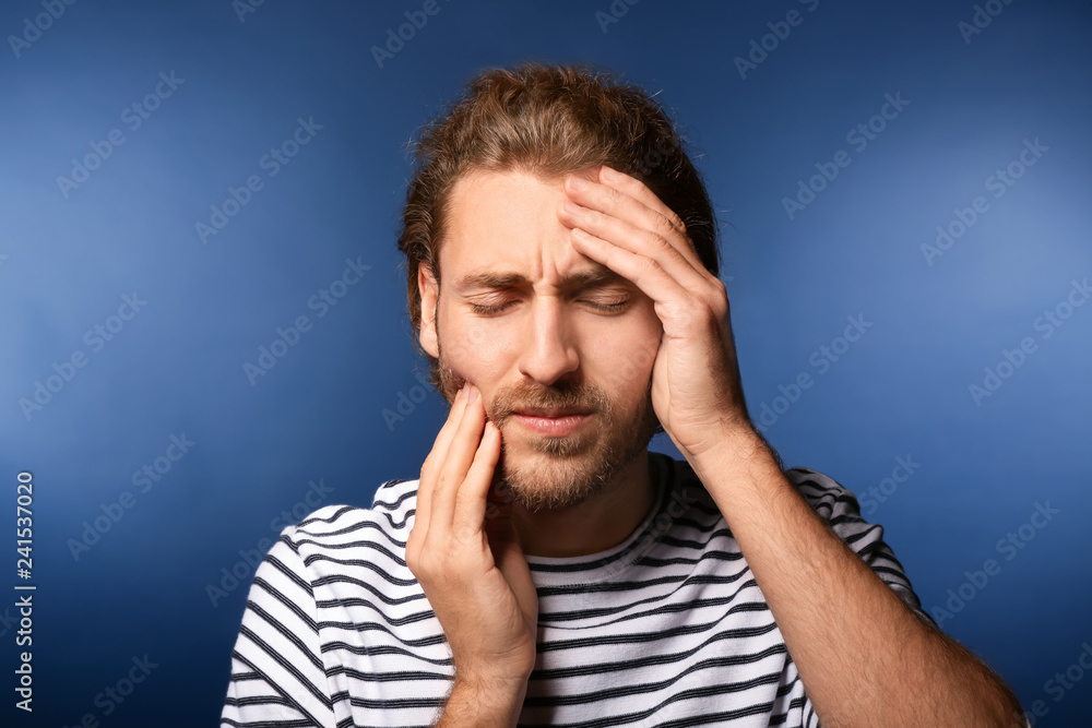 Young man suffering from headache on color background Young man suffering from headache on color background