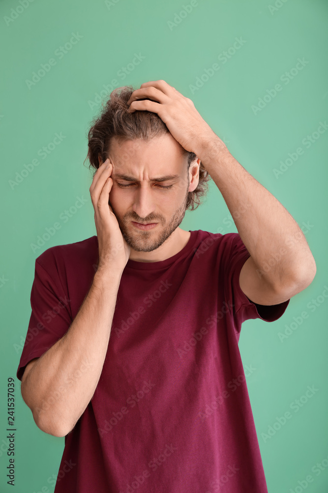 Young man suffering from headache on color background Young man suffering from headache on color background