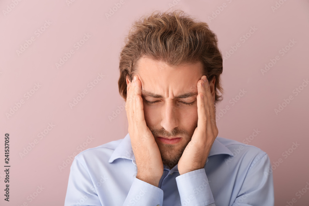 Young man suffering from headache on color background Young man suffering from headache on color background
