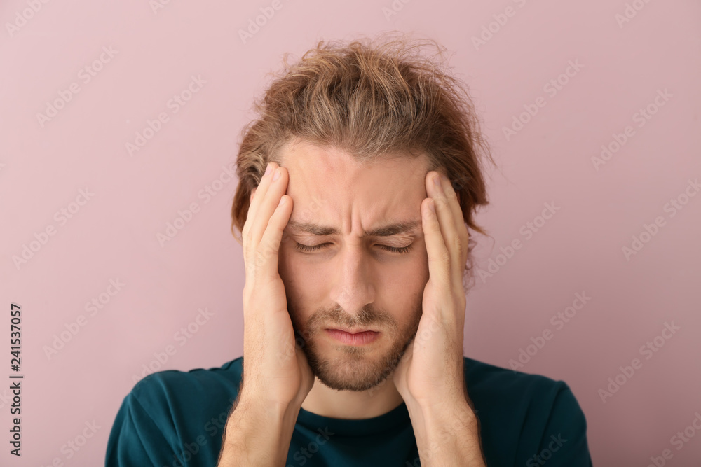 Young man suffering from headache on color background Young man suffering from headache on color background