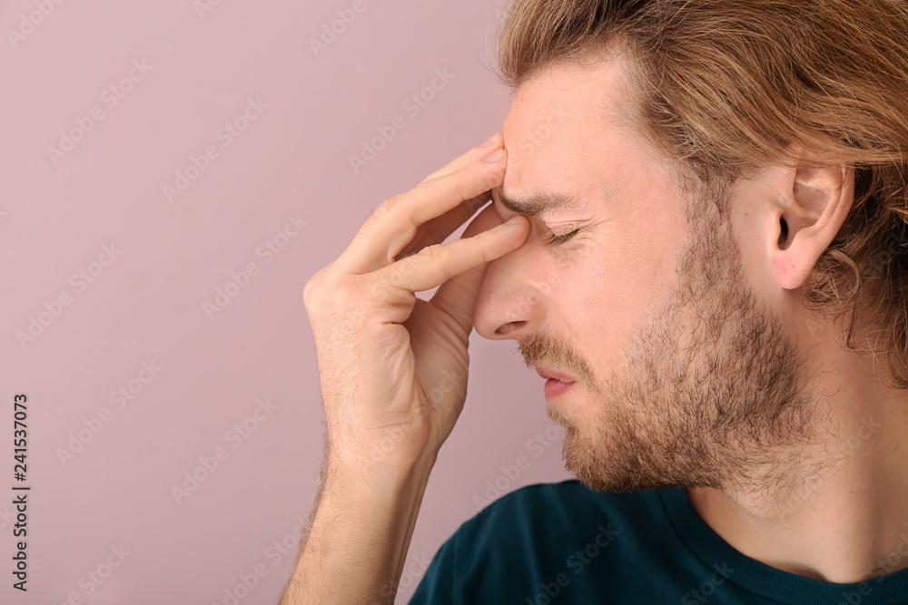 Young man suffering from headache on color background