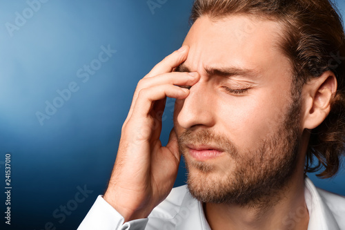 Young man suffering from headache on color background