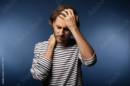 Young man suffering from headache on color background