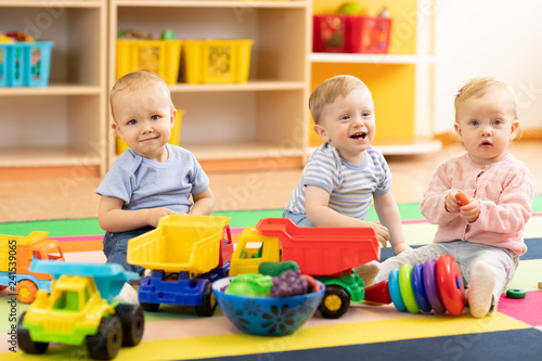 Group of babies is playing on floor in nursery. Children in the day care center. Fun in the children's playroom