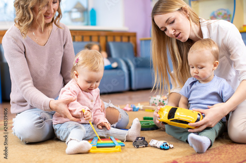 Babies play and their mothers communicate in playroom