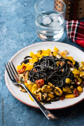 Black pasta with seafood, anchovies, tomatoes and bell peppers. © FoodAndPhoto