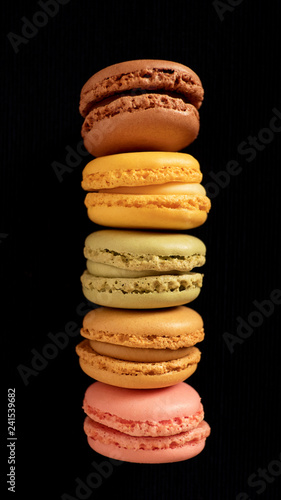 Fototapeta Naklejka Na Ścianę i Meble -  Assortment of traditional French macaroons or macarons, selection of different colors and flavors, very light bite-size confectionery, stacked high and  isolated against black background