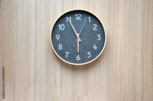 wooden clock shown early morning time on light wooden wall.