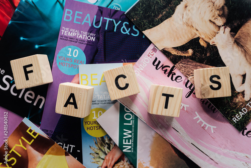 Fotografi top view of pile of different tabloid magazines and wooden cubes with word facts