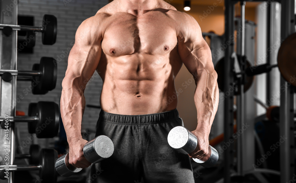 Muscular man training with dumbbells in gym Muscular man training with dumbbells in gym