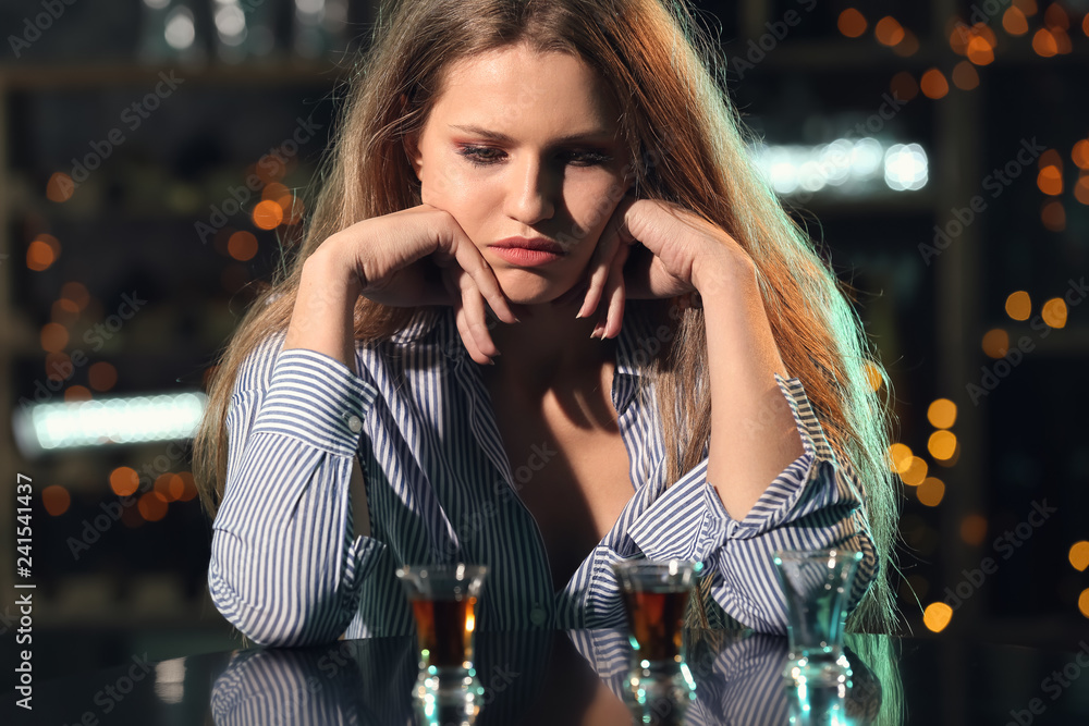 Young woman drinking alcohol in bar