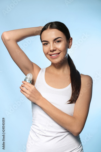 Young woman using deodorant...