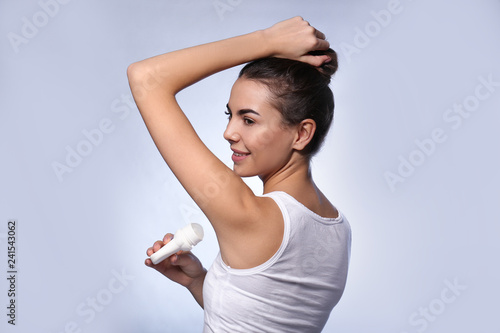 Young woman using deodorant...