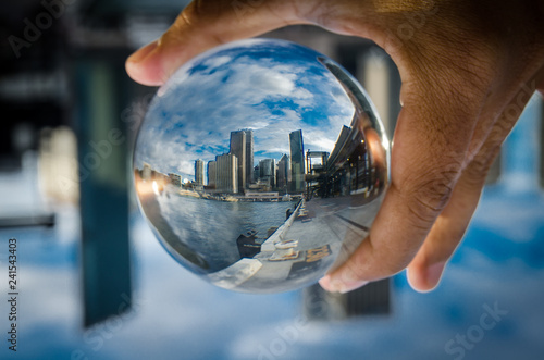 Cityscape photography in a clear glass crystal ball with dramatic clouds sky.