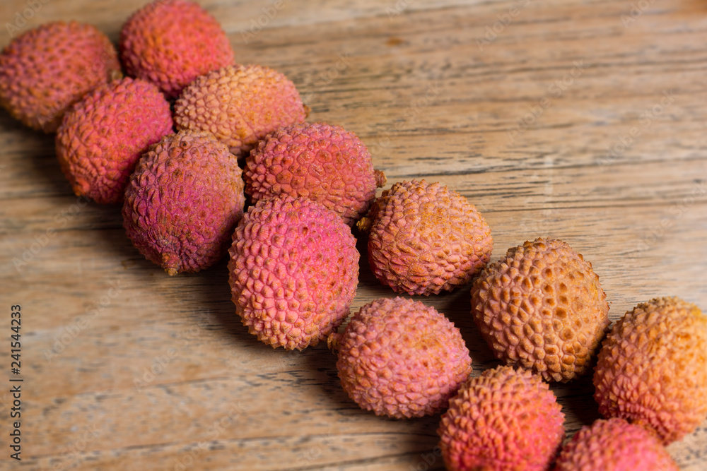 Raw pink and orange lychees on a wooden background Raw pink and orange lychees on a wooden background