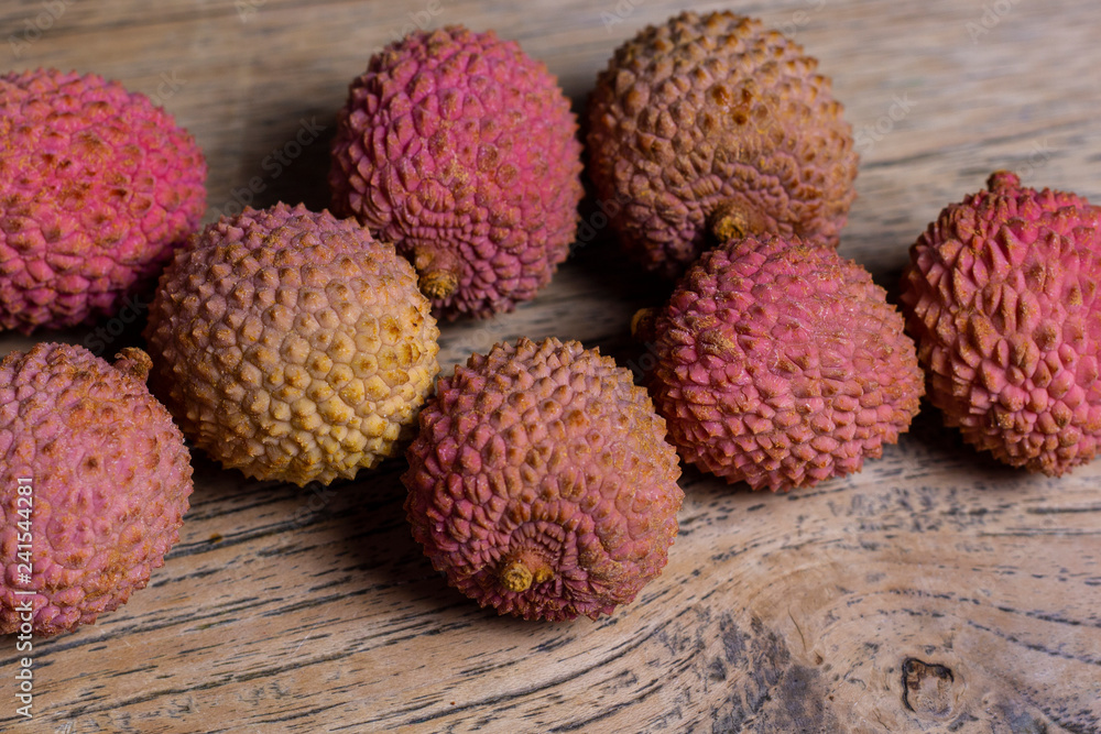 Raw pink and orange lychees on a wooden background Raw pink and orange lychees on a wooden background