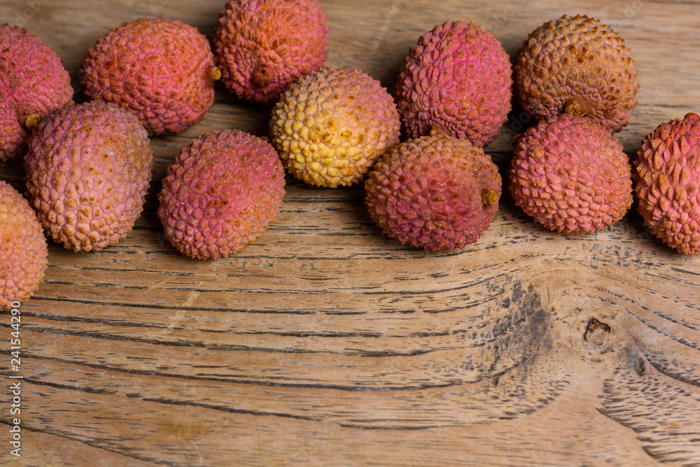 Raw pink and orange lychees on a wooden background Raw pink and orange lychees on a wooden background