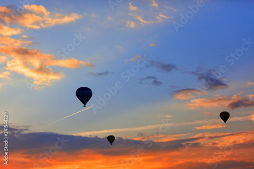 Silhouettes of balloons on the background of the morning sky with fiery red clouds.