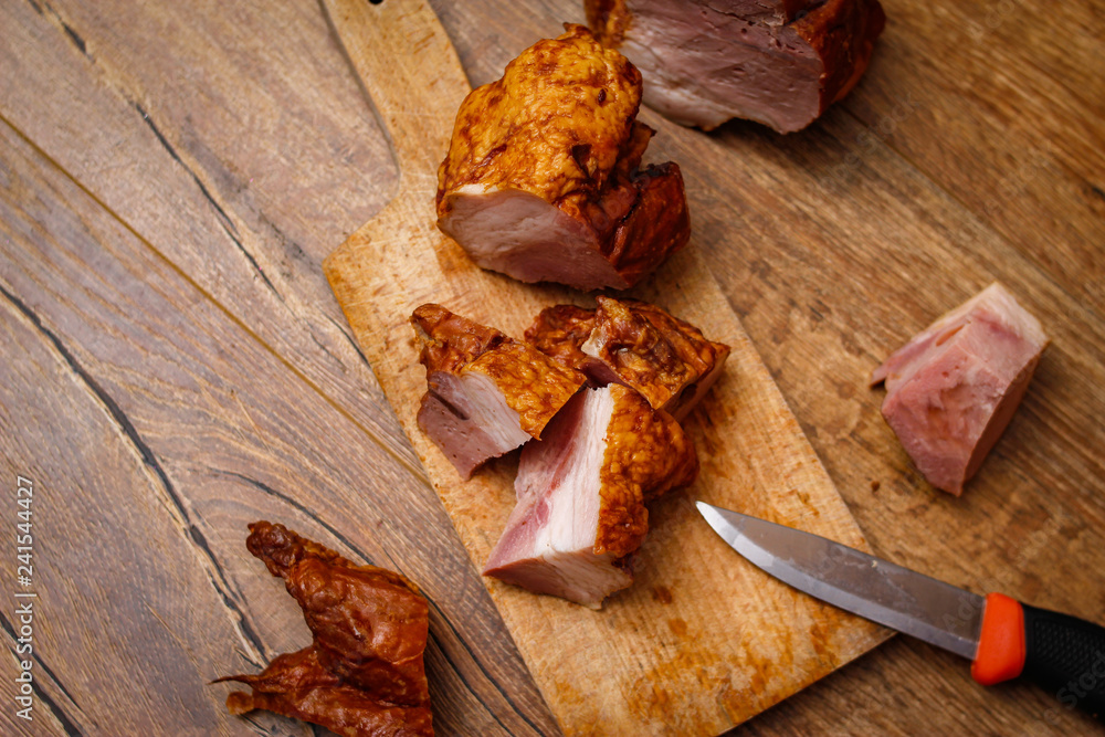 Smoked meat on cutting board. Vintage wooden table.