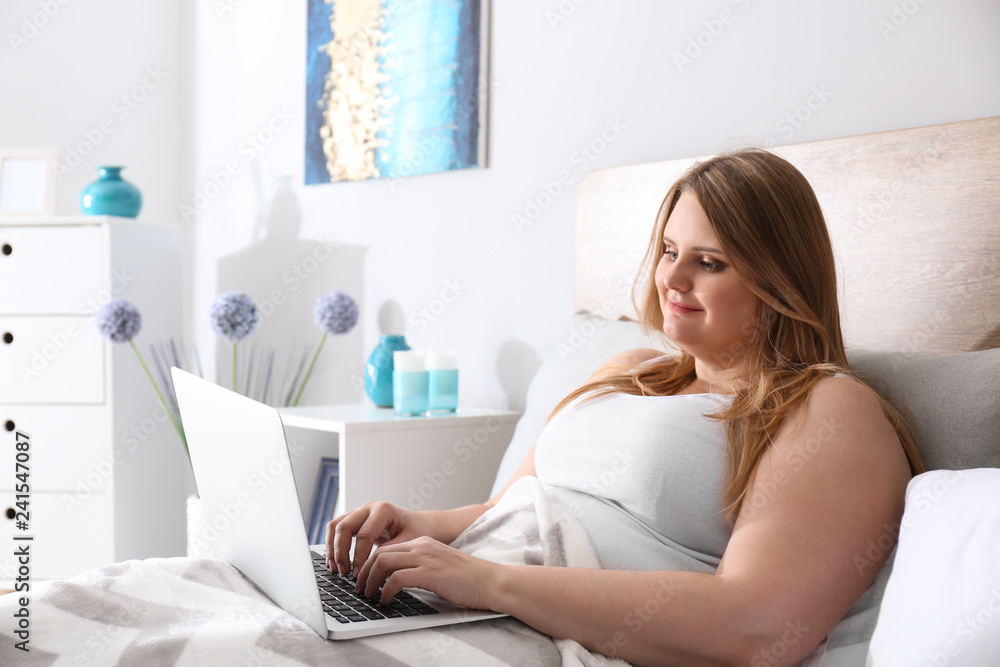 Beautiful plus size girl with laptop resting at home. Concept of body positivity Beautiful plus size girl with laptop resting at home. Concept of body positivity