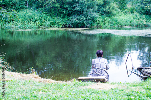 lonely woman sitting on the shore of a forest lake
