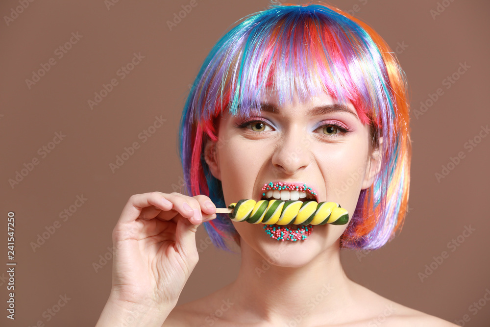 Beautiful young woman with unusual makeup and sweet lollipop on color background Beautiful young woman with unusual makeup and sweet lollipop on color background