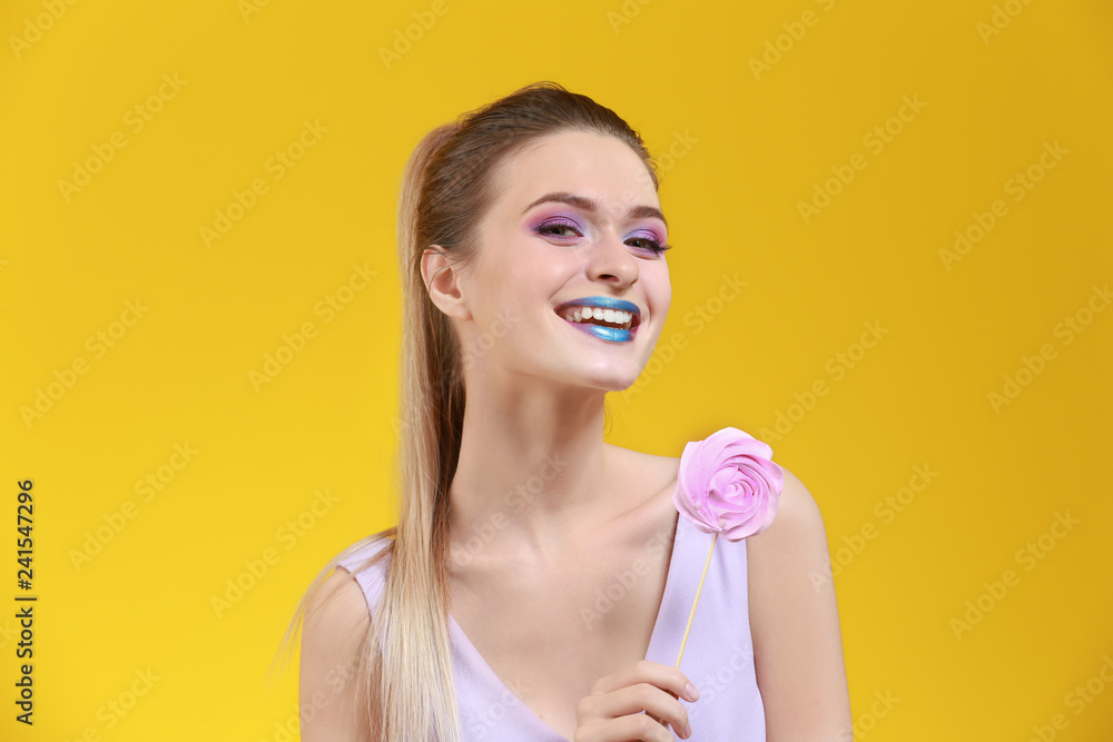 Beautiful young woman with unusual makeup and sweet lollipop on color background Beautiful young woman with unusual makeup and sweet lollipop on color background