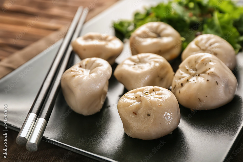 Plate with tasty Chinese dumplings on table, closeup