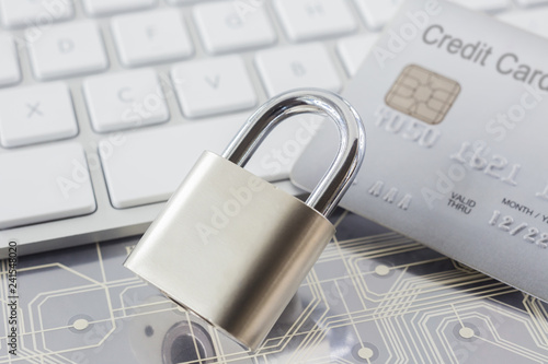 Padlock and credit card on keyboard and electronic circuits.