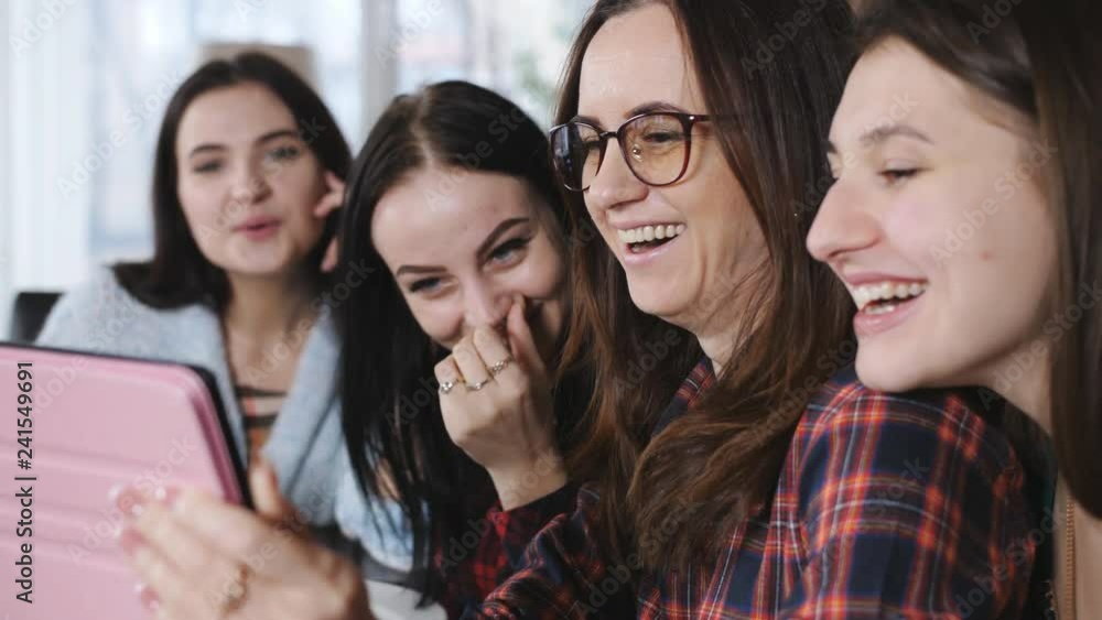 Four cheerful girlfriends in a restaurant eating pizza, drinking beer and watching photos on tablet. Four cheerful girlfriends in a restaurant eating pizza, drinking beer and watching photos on tablet.