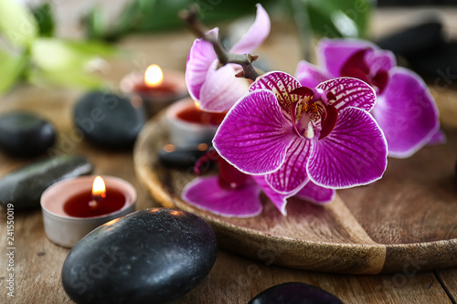 Beautiful spa composition with stones, candles and flowers on table, closeup