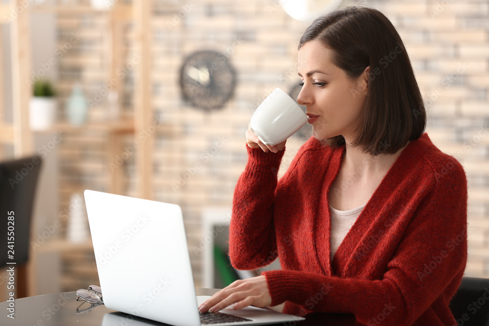 Young woman drinking coffee while working with laptop at home Young woman drinking coffee while working with laptop at home