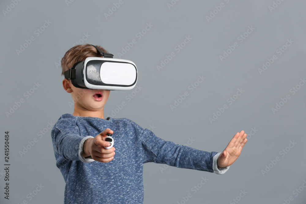 Cute boy with virtual reality glasses on grey background Cute boy with virtual reality glasses on grey background