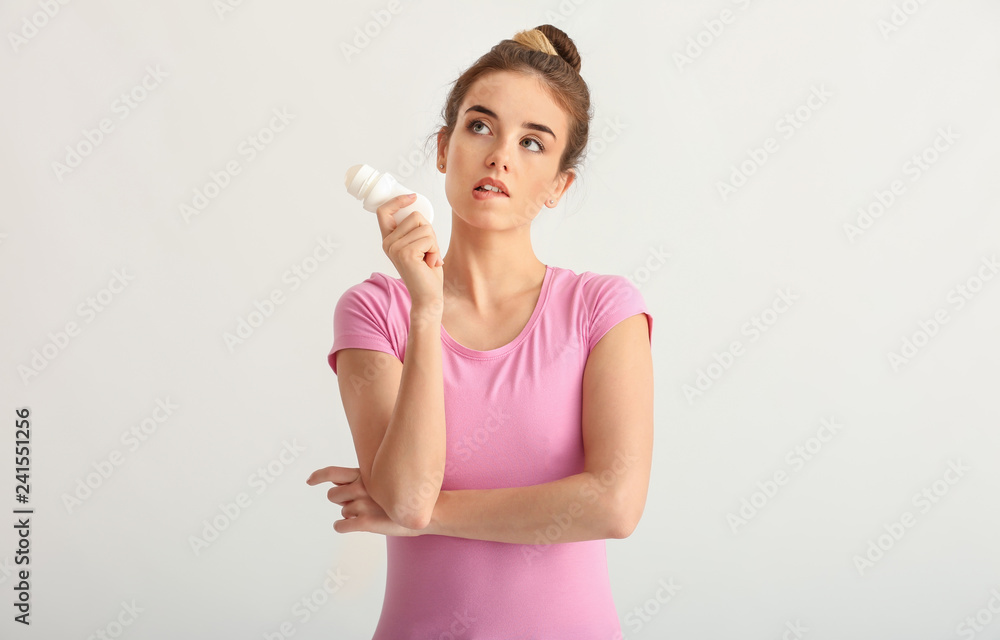 Beautiful young woman with deodorant on light background Beautiful young woman with deodorant on light background